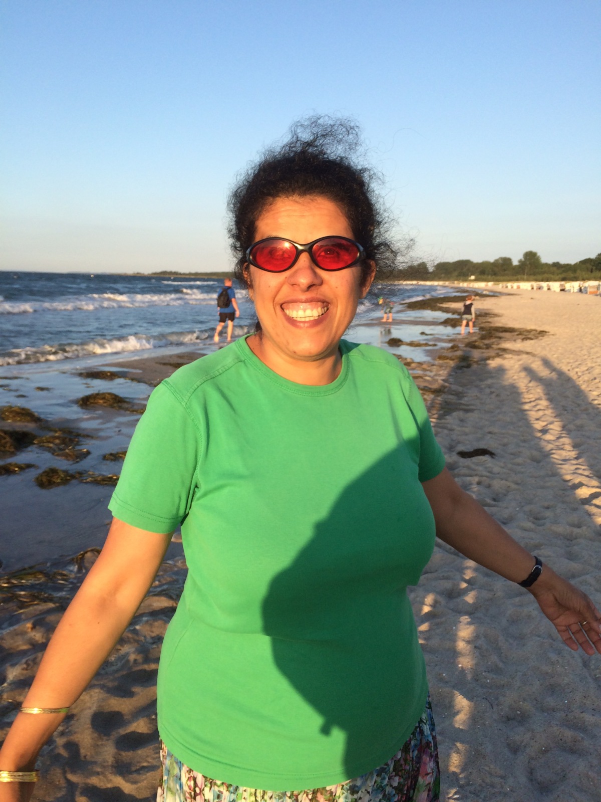 Lydia am Strand mit grünem T-Shirt und buntem Rock