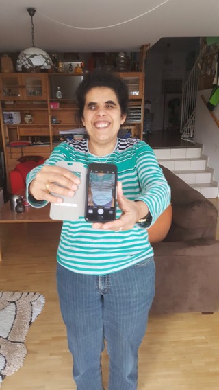 Lydia hält lächelnd ein iPhone vor der Brust.