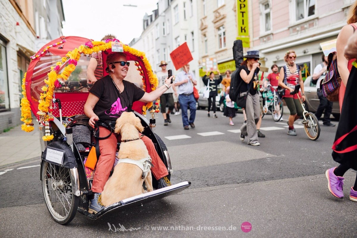 Andrea Eberl lächelnd mit Blindenführhund in einer Fahrradrikscha