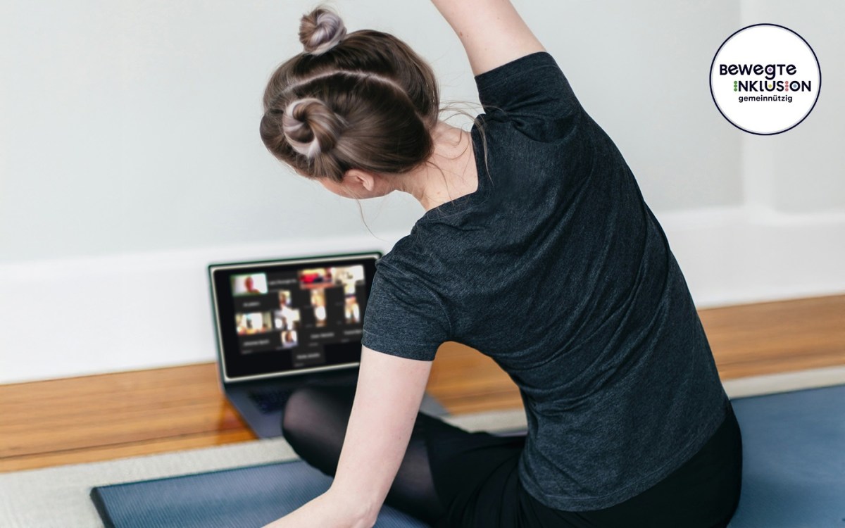Eine blinde Frau sitzt im Schneidersitz auf einer Sportmatte, mit dem Rücken zur Kamera. Sie neigt ihren Oberkörper nach links und streckt den rechten Arm dehnend über den Kopf. Vor ihr steht ein Laptop auf dem Boden, der einen Online-Kurs per Zoom zeigt. In der oberen rechten Ecke ist klein das Logo „Bewegte Inklusion“ zu sehen.